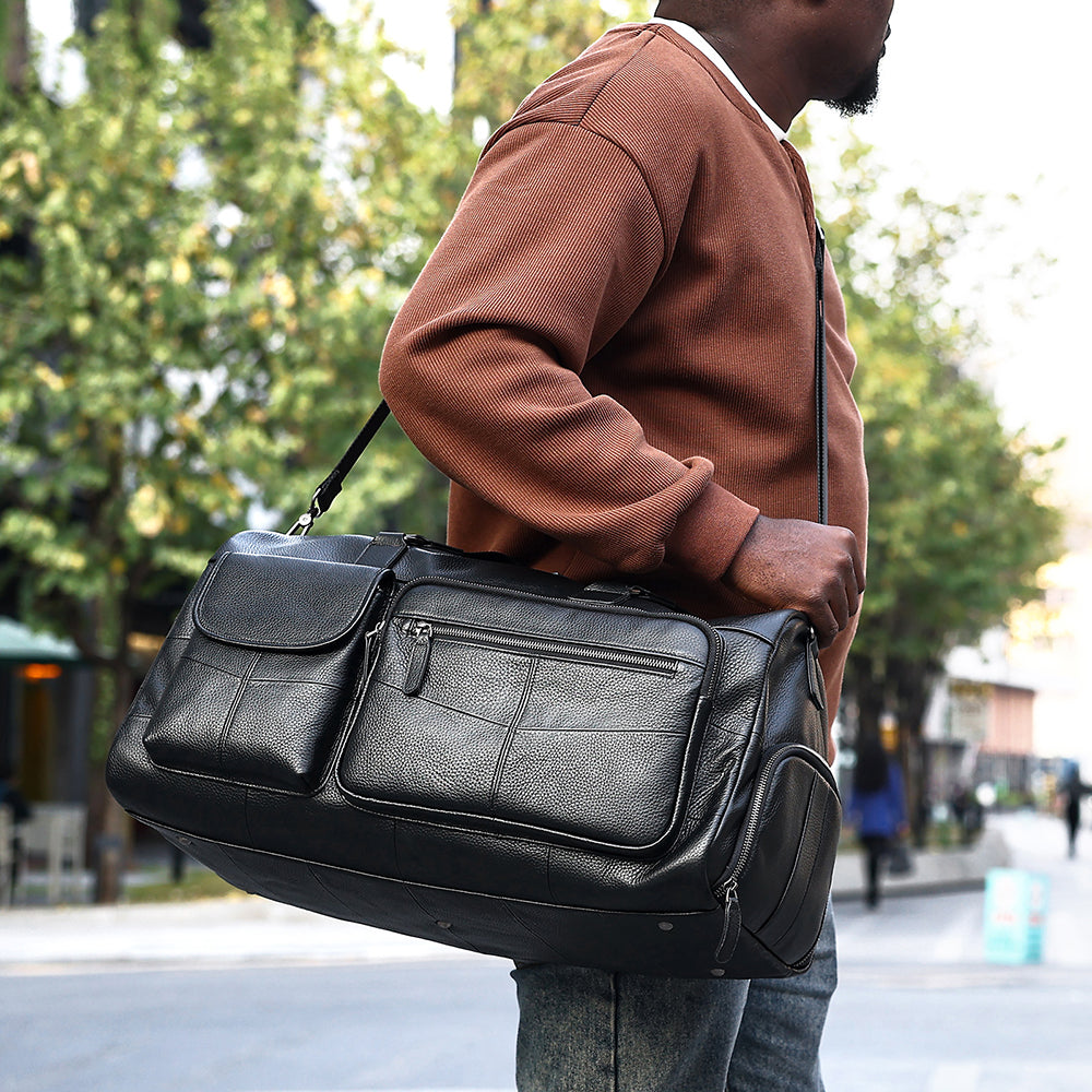 Black cowhide travel duffel carried outdoors by hand