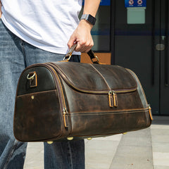 Dark brown leather travel duffel bag, handheld outdoor lifestyle view