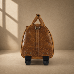 End view of cognac floral leather duffle showing two wheels