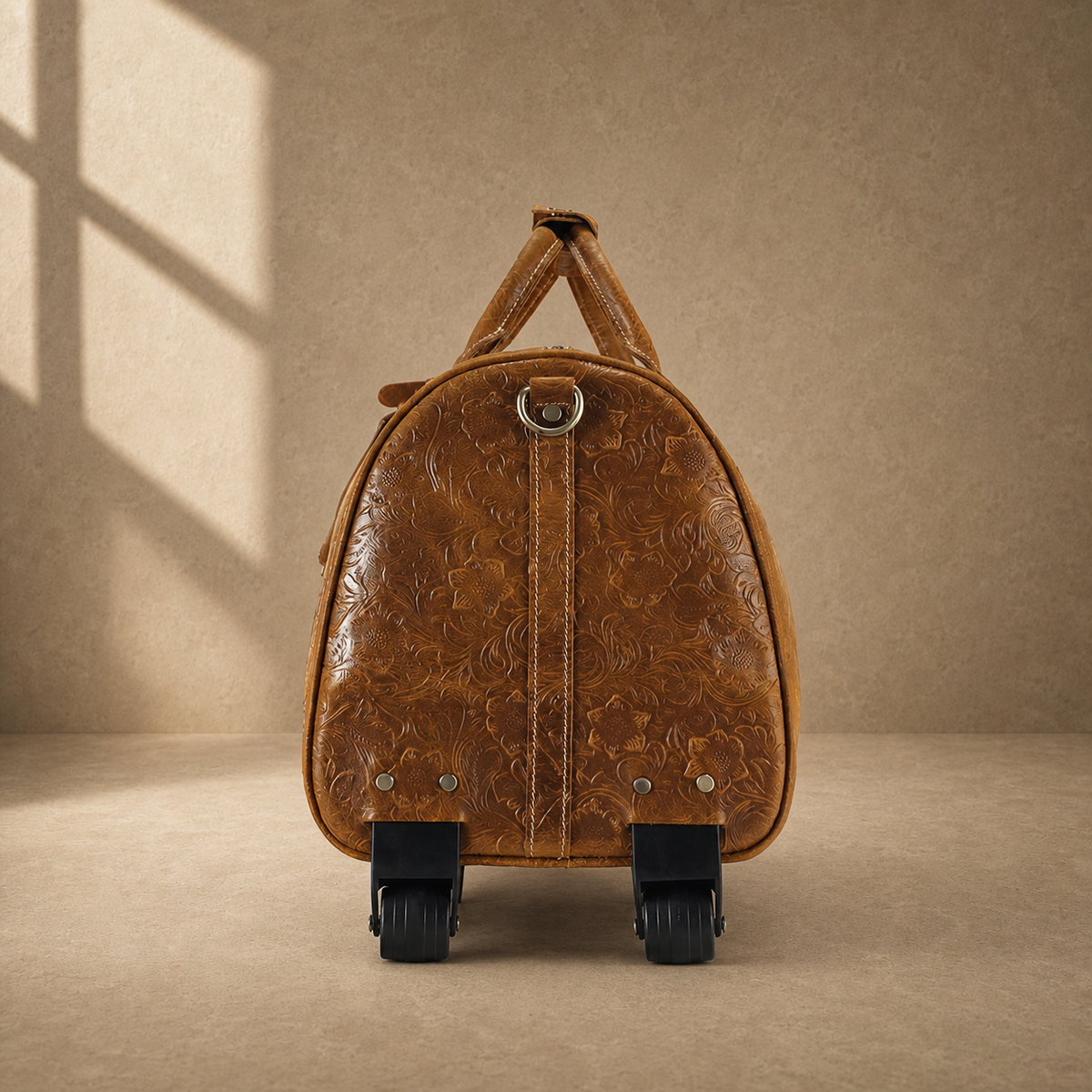End view of cognac floral leather duffle showing two wheels