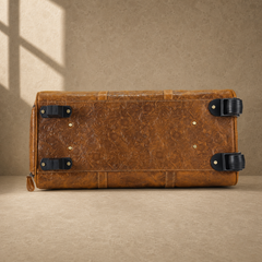 Base view of cognac rolling duffle showing wheels and protective feet
