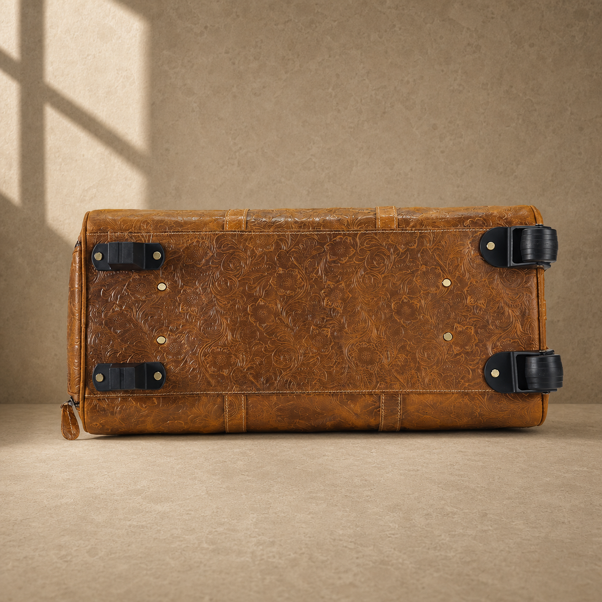 Base view of cognac rolling duffle showing wheels and protective feet