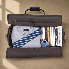Open brown rolling garment bag packed with shirt, tie, books and phone
