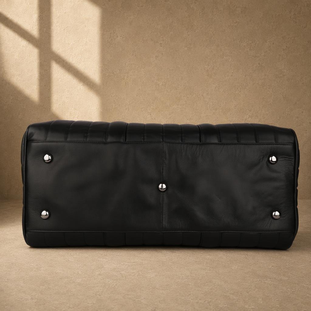 Black quilted cowhide travel duffel with protective metal feet