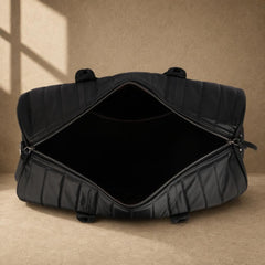 Black quilted cowhide travel duffel showing empty main compartment