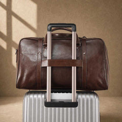 Coffee cowhide executive travel tote secured to suitcase handle