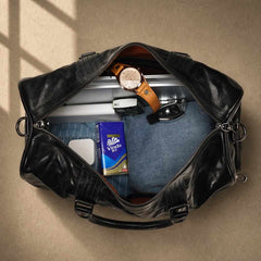 Overhead view of packed cowhide leather weekender with laptop and travel essentials