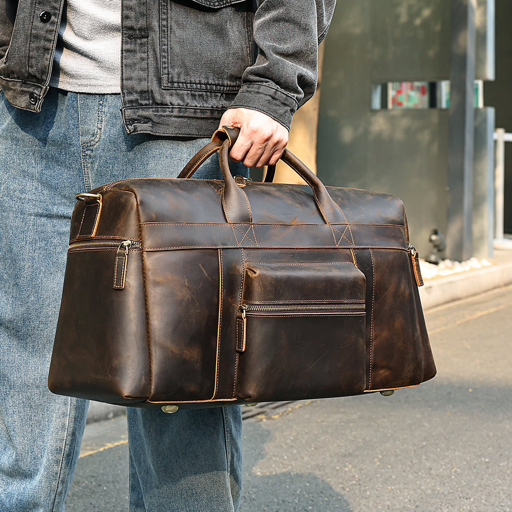 Dark brown cowhide travel duffel bag, handheld lifestyle view